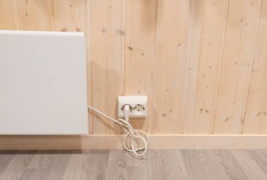 Ahşap duvarın altındaki ısıtıcının elektrik fişi 