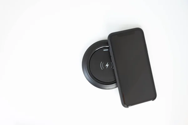 Teléfono móvil negro y cargador inalámbrico en la pantalla blanca —  Fotos de Stock