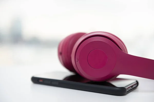 Fechar Pink fone de ouvido sem fio e telefone inteligente no branco ta — Fotografia de Stock