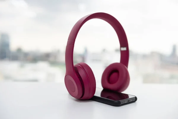 Pink vezeték nélküli fejhallgató és okos telefon a fehér asztalon — Stock Fotó