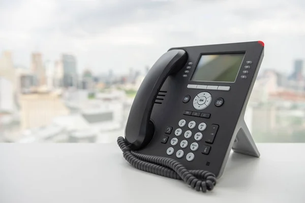 Telefone IP preto na mesa branca com fundo de paisagem da cidade — Fotografia de Stock