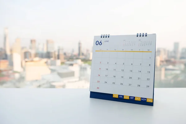 Calendário de junho na tabela branca com vista para a cidade fundo — Fotografia de Stock