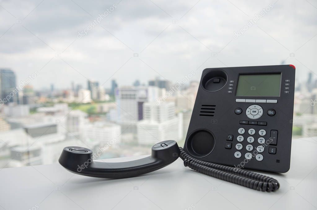Black IP Phone on the white table with city scape background