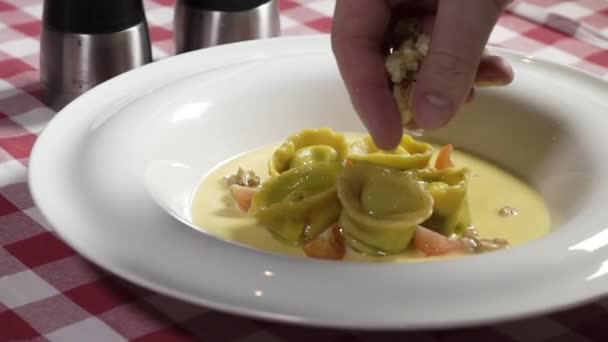 Kock händer strössel ost på dumplings i en tallrik på en rutig duk — Stockvideo