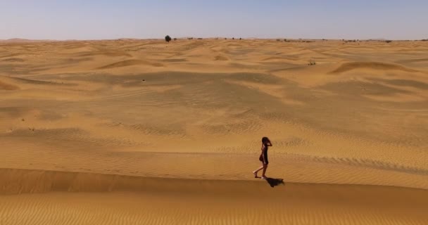 Meisje loopt langs een duin in de woestijn. — Stockvideo
