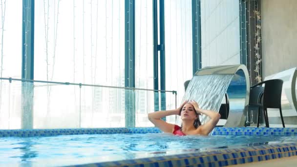 Giovane donna in piscina sotto cascata artificiale — Video Stock