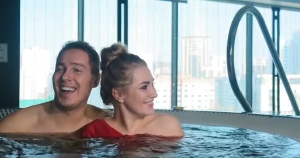 Radosna para śmieje się i przytula siedząc w wirowej wodzie — Wideo stockowe