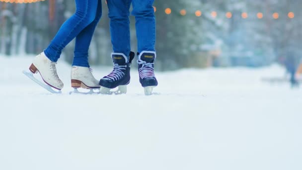 Pareja en pantalones vaqueros azules y patines puestos en pista de hielo pública — Vídeo de stock
