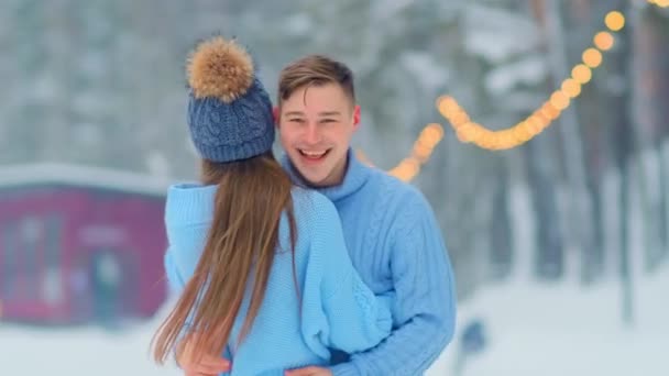 Abrazos de pareja girando en pista de patinaje abierto con guirnaldas — Vídeo de stock