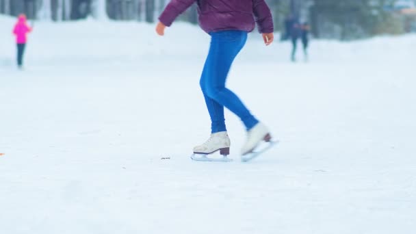 Jeune femme avec queue de cheval en veste tourne sur les patins sur la patinoire — Video