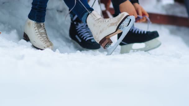 Mädchen und Mann schnüren Eiskunstläufer zum Ausruhen auf offener Eisbahn — Stockvideo