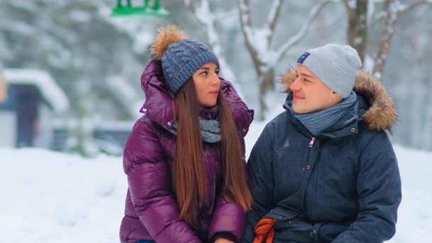 Κορίτσι και ο φίλος σε σακάκια μιλούν κάθεται στο χιονισμένο πάρκο — Αρχείο Βίντεο