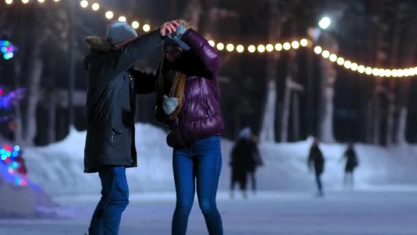 Gelukkig meisje in jas dansen met vriendje op schaatsbaan — Stockvideo
