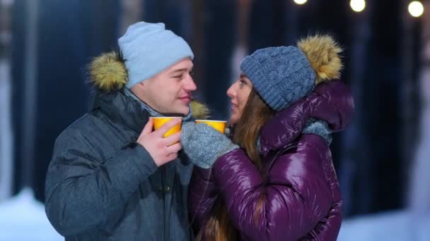 Sıcak ceketli erkek ve kız buz pistinde bir bardak sıcak içki içiyorlar. — Stok video