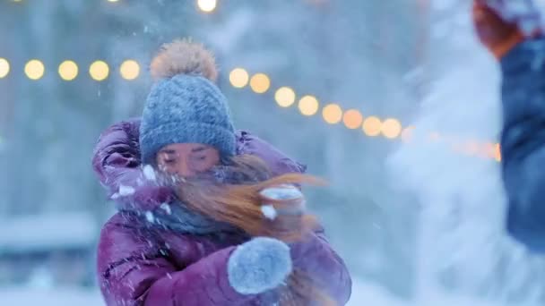 Pige i varm jakke og hat kaster sne med glad kæreste – Stock-video