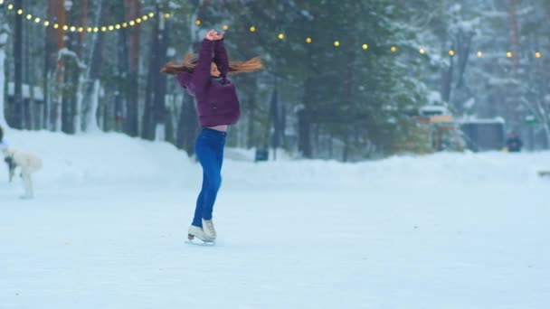 Lady with long hair spins on outdoor ice rink in evening — Stock Video