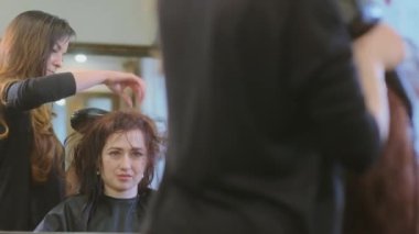 Usta, kuaförde saç kurutma makinesiyle esmer saçı kurutuyor.