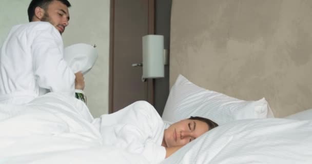 Muž probudí přítelkyni a představuje kytici v hotelovém pokoji — Stock video