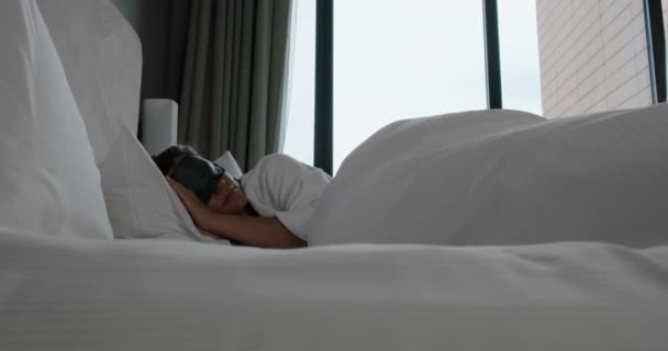 Женщина просыпается и снимает маску лежащей на удобной кровати — стоковое видео