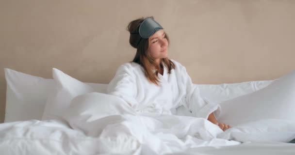 Mulher bonita se estende na cama confortável com travesseiros — Vídeo de Stock