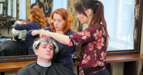 Перукарі беруть фольгу з відбілювачем від серйозного чоловіка волосся — стокове відео