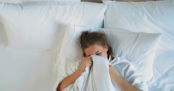女性は枕と毛布で快適なベッドの上に横たわっている — ストック動画