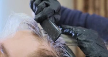 Siyah eldivenli güzellik salonu çalışanı çamaşır suyu kullanıyor.