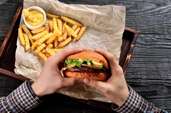 Man hold burger in hands. Meal with burger and french fries.