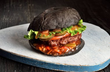 Ahşap arka plan üzerinde taze siyah burger. Seçilen odak.