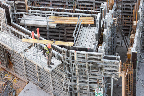 Worker carries wooden plank onto concrete formwork