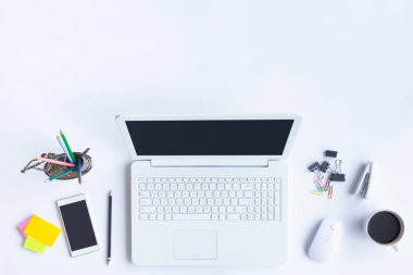 Bilgisayarlı beyaz masa ofisi, akıllı telefon ve bir fincan kahveli diğer iş malzemeleri. Metni kopyalamak için üst görünümü kullan. Desenci çalışma alanı düz masa üzerinde temel elementler yatıyordu.
