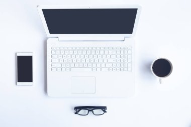 Bilgisayarlı beyaz masa ofisi, akıllı telefon ve bir fincan kahveli diğer iş malzemeleri. Metni kopyalamak için üst görünümü kullan. Desenci çalışma alanı düz masa üzerinde temel elementler yatıyordu.