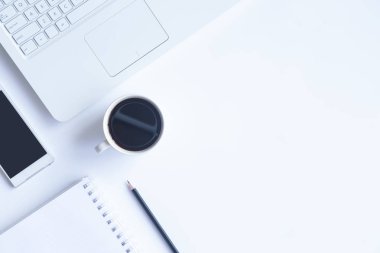 Bilgisayarlı beyaz masa ofisi, akıllı telefon ve bir fincan kahveli diğer iş malzemeleri. Metni kopyalamak için üst görünümü kullan. Desenci çalışma alanı düz masa üzerinde temel elementler yatıyordu.