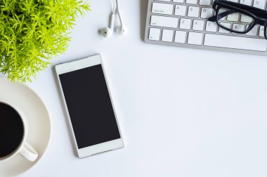 Bilgisayarlı beyaz masa ofisi, akıllı telefon ve bir fincan kahveli diğer iş malzemeleri. Metni kopyalamak için üst görünümü kullan. Desenci çalışma alanı düz masa üzerinde temel elementler yatıyordu.