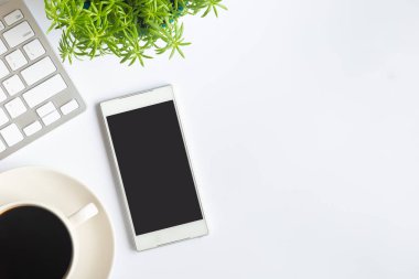 Bilgisayarlı beyaz masa ofisi, akıllı telefon ve bir fincan kahveli diğer iş malzemeleri. Metni kopyalamak için üst görünümü kullan. Desenci çalışma alanı düz masa üzerinde temel elementler yatıyordu.