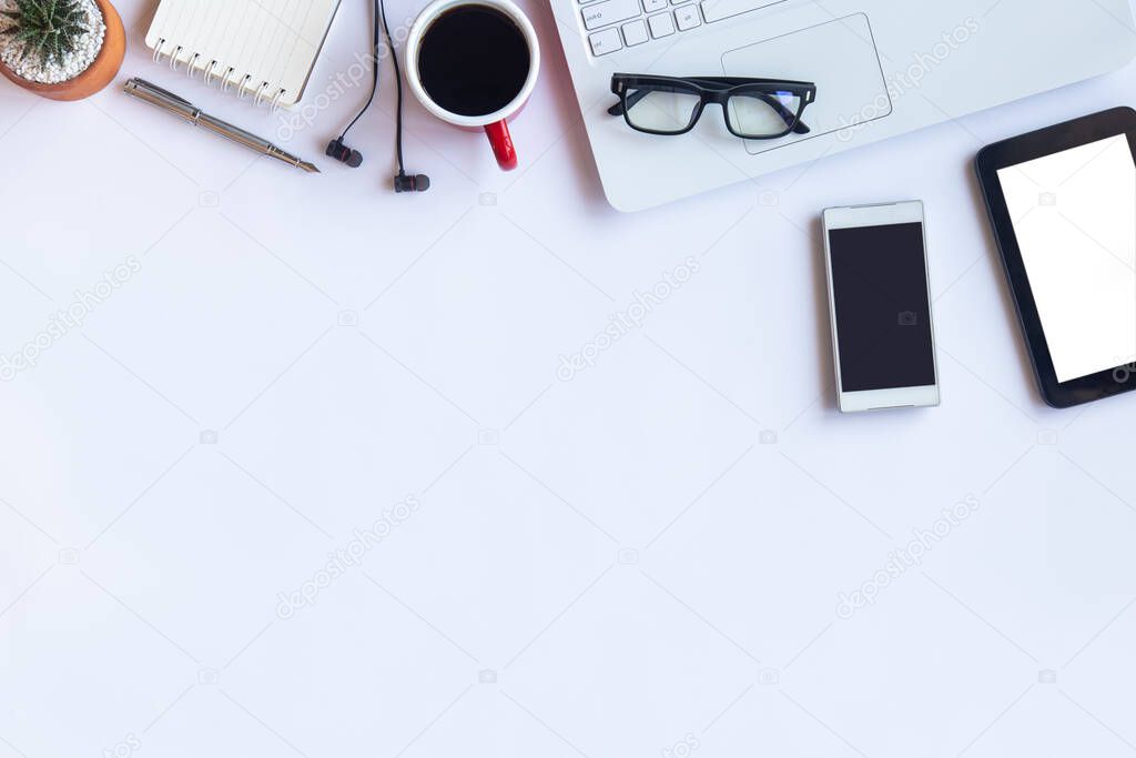 White desk office with laptop, smartphone and other work supplies with cup of coffee. Top view with copy space for input the text. Designer workspace on desk table essential elements on flat lay.