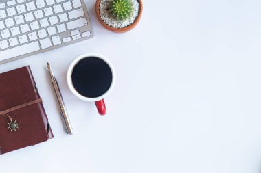 Bilgisayarlı beyaz masa ofisi, akıllı telefon ve bir fincan kahveli diğer iş malzemeleri. Metni kopyalamak için üst görünümü kullan. Desenci çalışma alanı düz masa üzerinde temel elementler yatıyordu.