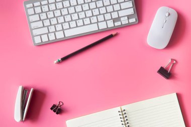 Dizüstü bilgisayarı, akıllı telefonu ve bir fincan kahveli diğer iş malzemeleri olan Pastel Pembe ofis. Metni kopyalamak için üst görünümü kullan. Çalışma alanı düz zeminde masa başı temel elementler üzerine.
