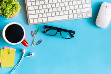 Dizüstü bilgisayarı, akıllı telefonu ve bir fincan kahveli diğer iş malzemeleri olan Pastel Blue ofis. Metni kopyalamak için üst görünümü kullan. Çalışma alanı düz zeminde masa başı temel elementler üzerine.