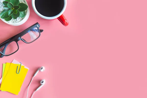 Pastel pink desk office with laptop, smartphone and other work supplies with cup of coffee. Top view with copy space for input the text. Workspace on desk table essential elements on flat lay.