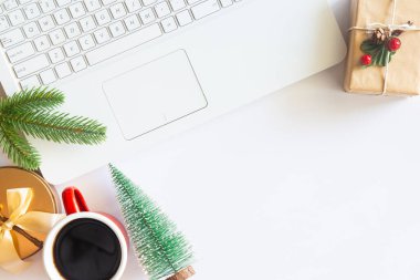 Beyaz Noel, dizüstü bilgisayarlı masa başı ofisi, dekorasyon ve bir fincan kahve ile iş malzemeleri. Metni kopyalamak için üst görünümü kullan. Kış Noel 'inde masa düzleşmişti. İş Tatili Konsepti.