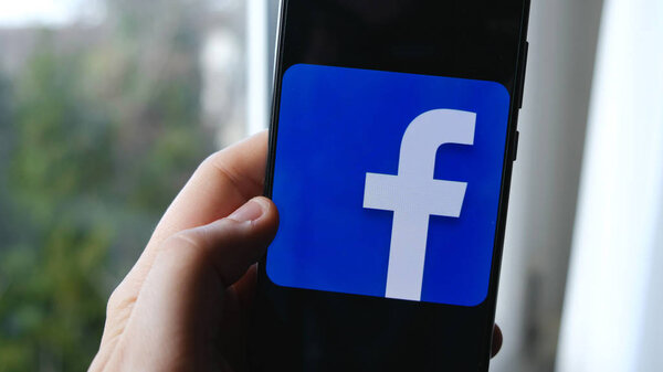 hand and finger use facebook app symbol on a smartphone