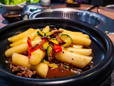 Kore Tteokbokki pirinç köfte siyah çanak Kore etnik restoranda tatlı ganjang soya sosu et ve kabak çan biber sebzeler ile