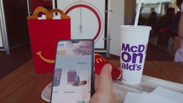 Ordenar comida de Mc Donalds en línea en un restaurante de comida rápida McDonald con smartphone — Vídeos de Stock