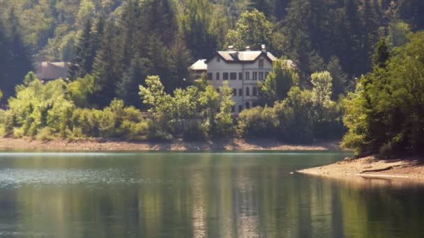 Sonbahar gölü sıcacık tonlarıyla su üzerinde yansımaları olan bina. — Stok video