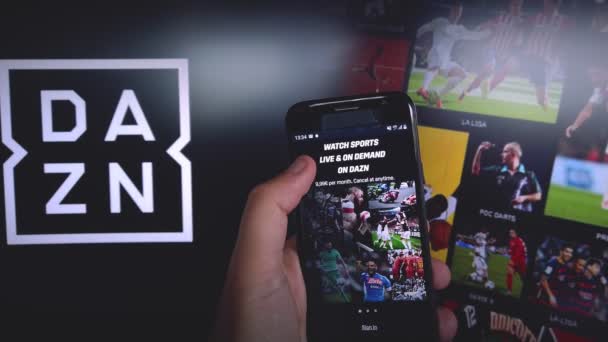 DAZN app for mobile phone with DAZN background - DAZN is a subscription sports streaming service with on demand and live events — Stock Video