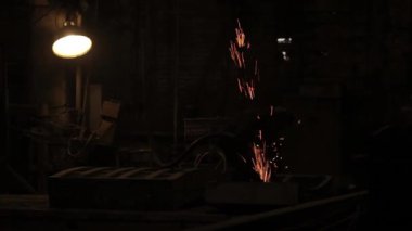 Metalurji üretim. Kaynakçı metal ile çalışır. Yakıcı fly farklı yönlere kıvılcım. Işınları ışık ve duman bulutları.