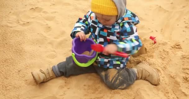 Kind wühlt eiskalt im Sand — Stockvideo