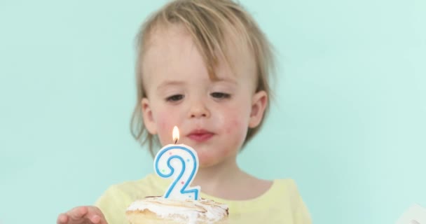 Мальчик со свечой на торте на 2 дня рождения — стоковое видео