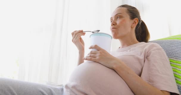 Fröhliche schwangere junge Frau isst Eis — Stockvideo